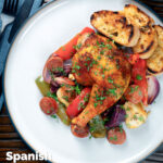 Overhead Spanish chicken and chorizo tray bake with vegetables served with toasted bread featuring a title overlay.