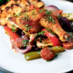 Spanish chicken and chorizo tray bake with vegetables served with toasted bread.