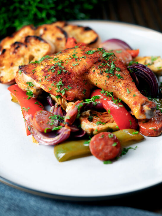 Spanish chicken and chorizo tray bake with vegetables served with toasted bread.