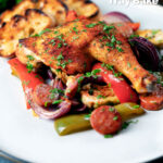 Spanish chicken and chorizo tray bake with vegetables served with toasted bread featuring a title overlay.