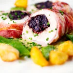 Close-up black pudding stuffed chicken with a mustard sauce, potatoes and runner beans.