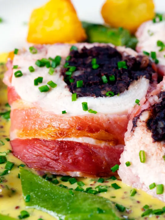 Close-up black pudding stuffed chicken breast wrapped in bacon.