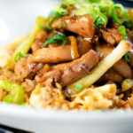Close-up ginger chicken with garlic and spring onions served with egg fried rice.