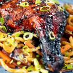 Close-up Chinese style char siu chicken leg served with sweet and sour noodles.