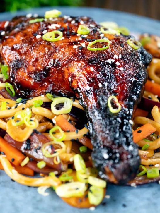 Close-up Chinese style char siu chicken leg served with sweet and sour noodles.