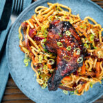 Overhead Chinese style char siu chicken leg served with sweet and sour noodles.