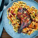 Overhead Chinese style char siu chicken leg served with sweet and sour noodles.