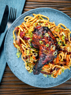 Overhead Chinese style char siu chicken leg served with sweet and sour noodles.