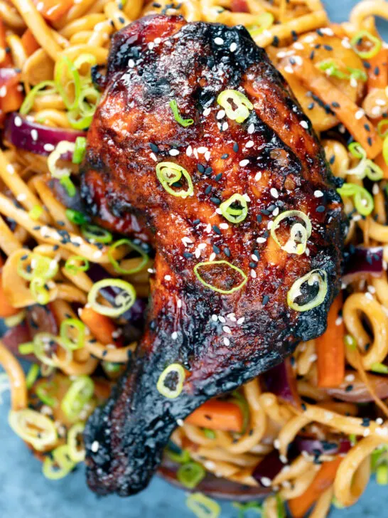 Overhead close-up Chinese style char siu chicken leg served with sweet and sour noodles.