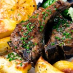 Close-up Greek lamb chops served with lemon garlic potatoes.