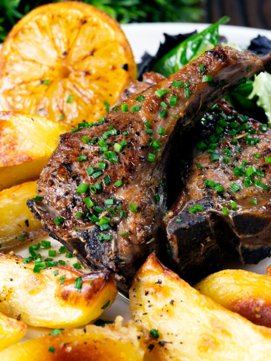 Close-up Greek lamb chops served with lemon garlic potatoes.