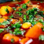 Close-up traditional Hungarian goulash soup or gulyásleves with csipetke (pasta), featuring a title overlay.