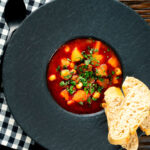 Overhead traditional Hungarian goulash soup or gulyásleves with csipetke (pasta), featuring a title overlay.