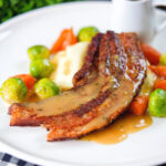Crispy roast pork belly slices with a cider sauce, mashed potato and veggies.
