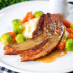 Crispy roast pork belly slices with a cider sauce, mashed potato and veggies.