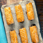 Overhead pork and apple sausage rolls with hot crusty pastry on a baking sheet.