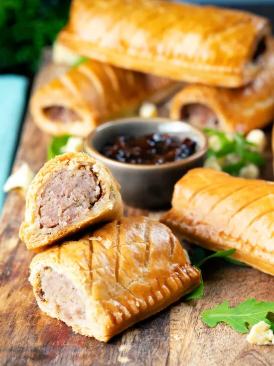 Homemade pork and apple sausage rolls with hot crust pastry cut open to show filling.