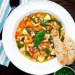 Overhead French soupe au pistou veggie soup served with bread.