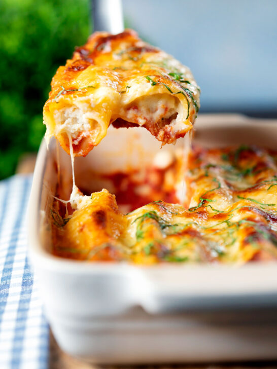 Close-up vegetarian cauliflower and ricotta cheese cannelloni being served from a baking dish.