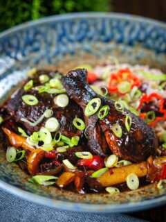 Spicy Jamaican brown stew chicken with spring onions and rice and peas.