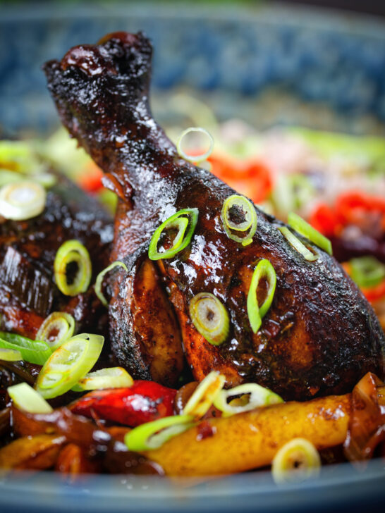 Close-up Jamaican brown stew chicken with spring onions.