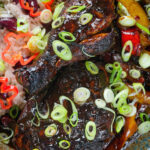 Close-up Overhead Jamaican brown stew chicken with spring onions, rice and peas.