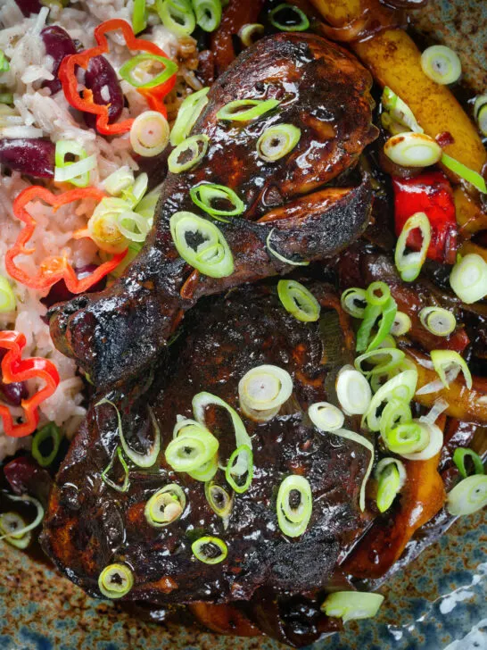 Close-up Overhead Jamaican brown stew chicken with spring onions, rice and peas.