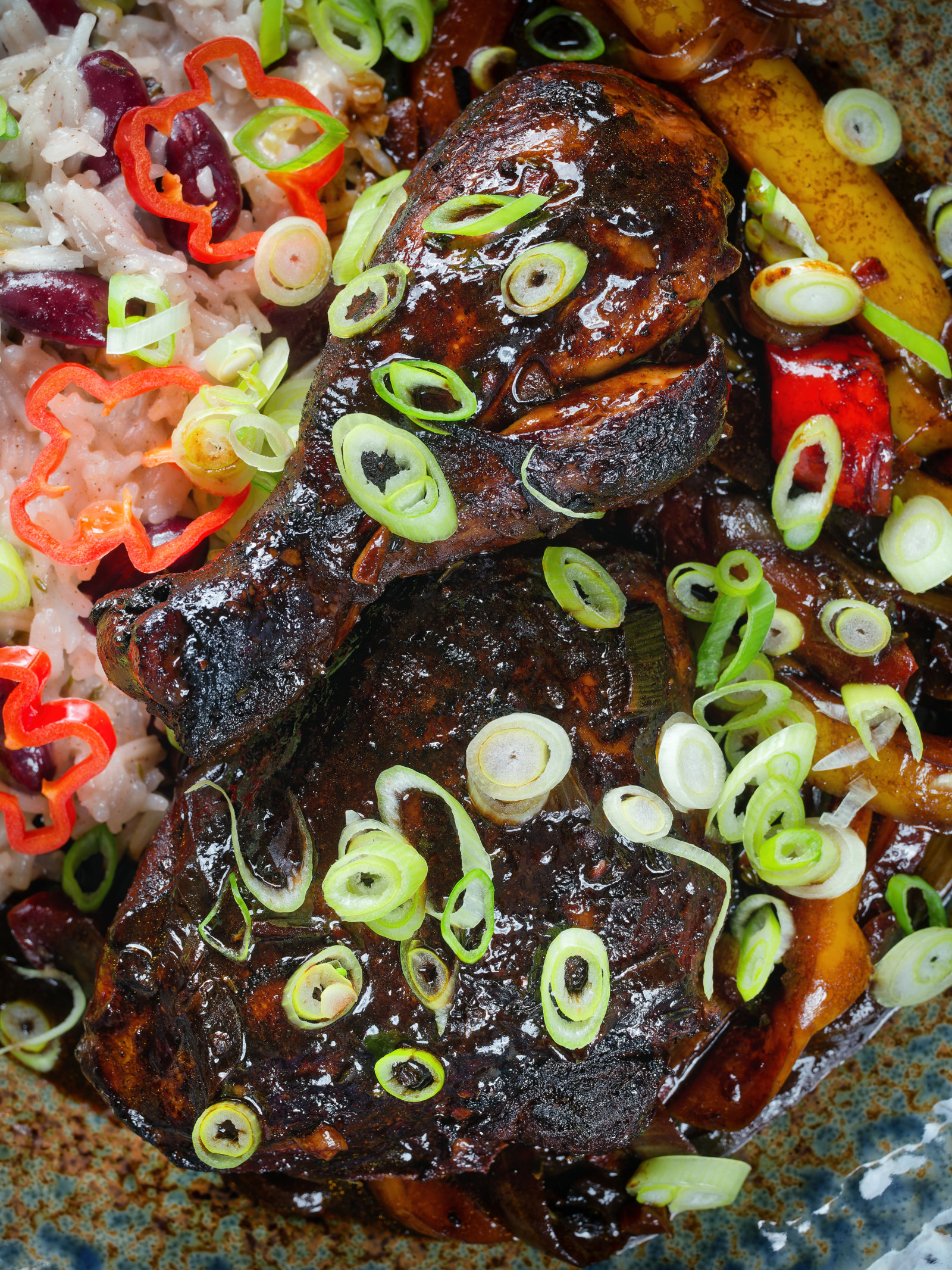 Close-up Overhead Jamaican brown stew chicken with spring onions, rice and peas.