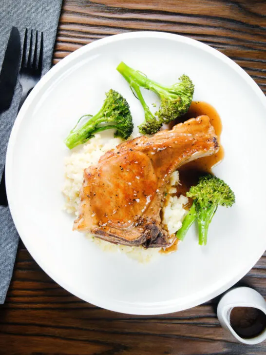 Overhead oven baked brown sugar pork chops served with celeriac mash and broccoli.