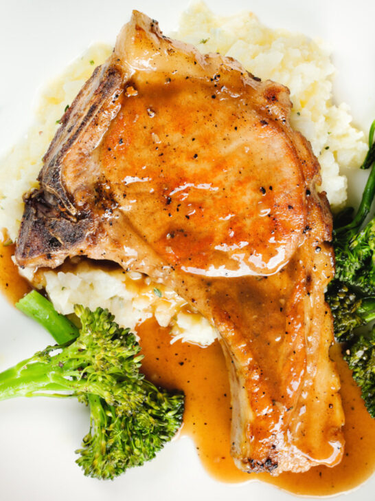 Overhead close-up oven baked brown sugar pork chops served with celeriac mash and broccoli.