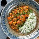 Overhead Indian carrot and chickpeas curry in a thick coconut milk sauce served with coriander rice.