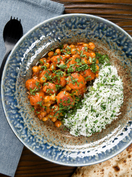 Overhead Indian carrot and chickpeas curry in a thick coconut milk sauce served with coriander rice.