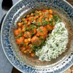 Overhead Indian carrot and chickpeas curry in a thick coconut milk sauce served with coriander rice.