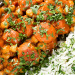 Overhead close-up carrot and chickpeas curry in a thick coconut milk sauce served with coriander rice.