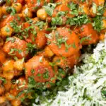Overhead close-up carrot and chickpeas curry in a thick coconut milk sauce served with coriander rice.