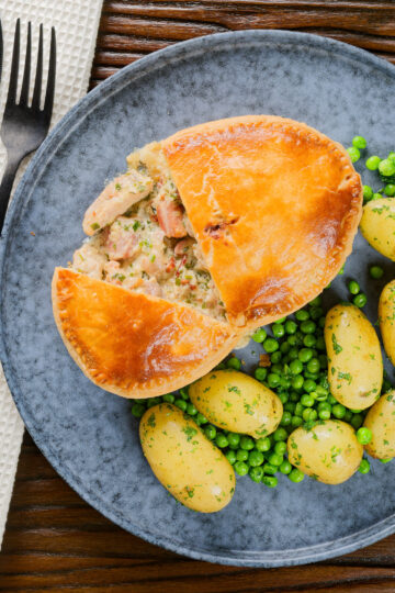 Overhead chicken and bacon pie cut open showing creamy filling with peas and potatoes.