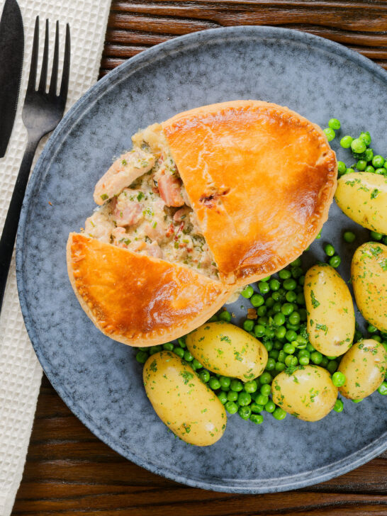 Overhead chicken and bacon pie cut open showing creamy filling with peas and potatoes.
