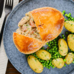 Overhead chicken and bacon pie cut open showing creamy filling with peas and potatoes.