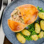 Overhead chicken and bacon pie cut open showing creamy filling with peas and potatoes.