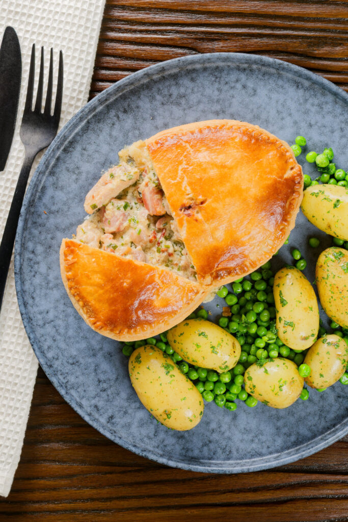 Overhead chicken and bacon pie cut open showing creamy filling with peas and potatoes.