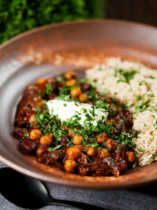 Vegan chickpea and kidney bean chilli served with coriander and rice.