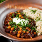 Vegan chickpea and kidney bean chilli served with coriander and rice.