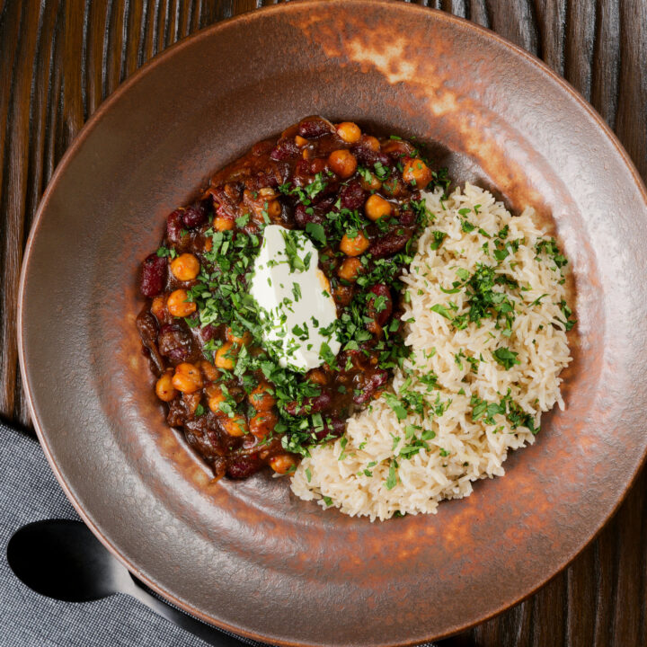 Spicy vegan chickpea and kidney bean chilli served with brown rice and coriander.