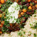 Overhead close-up vegan chickpea and kidney bean chilli served with coriander and rice.