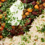 Overhead close-up vegan chickpea and kidney bean chilli served with coriander and rice.