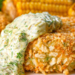 Close-up baked crab cakes with fennel and chives served with homemade tartar sauce.