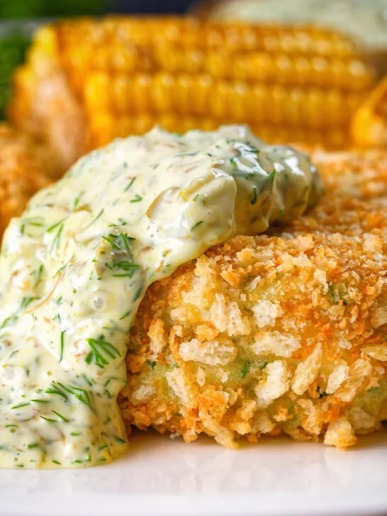 Close-up baked crab cakes with fennel and chives served with homemade tartar sauce.