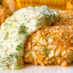 Close-up baked crab cakes with fennel and chives served with homemade tartar sauce.