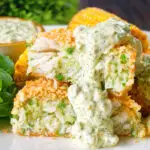 Homemade baked crab cakes cut open to show texture served with tartar sauce.