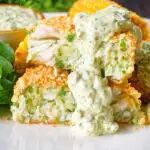 Homemade baked crab cakes cut open to show texture served with tartar sauce.